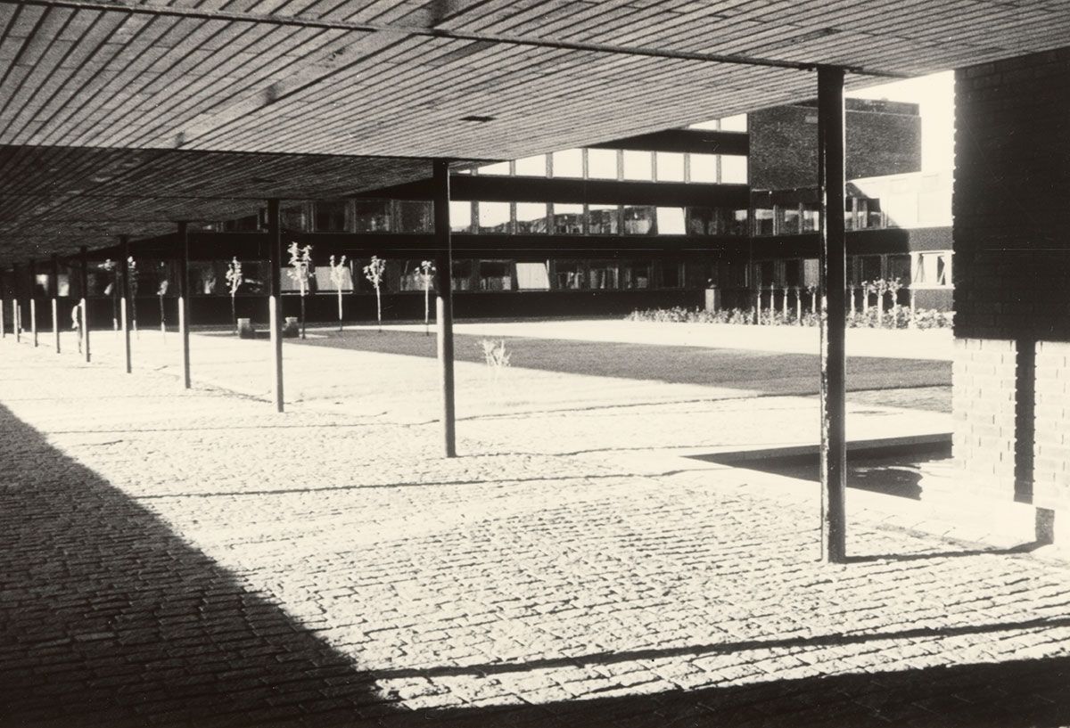 Brostein dekker også bakken under pergolaene som binder bygningene sammen utendørs. Her ser vi igjen inn mot Ivar Aasens hage. Til venstre ser vi to parallelle steinstøtter plassert på gresset. Fra dem renner det vann ut i et kar av stein. Denne &quot;fontenen&quot; skal være hentet fra Jernbanetorget i Oslo sentrum, og ble opprinnelig brukt som drikkekilde for tørste hester.&amp;#160;
1963-1965. Fotograf: Teigens fotoatelier.&amp;#160;