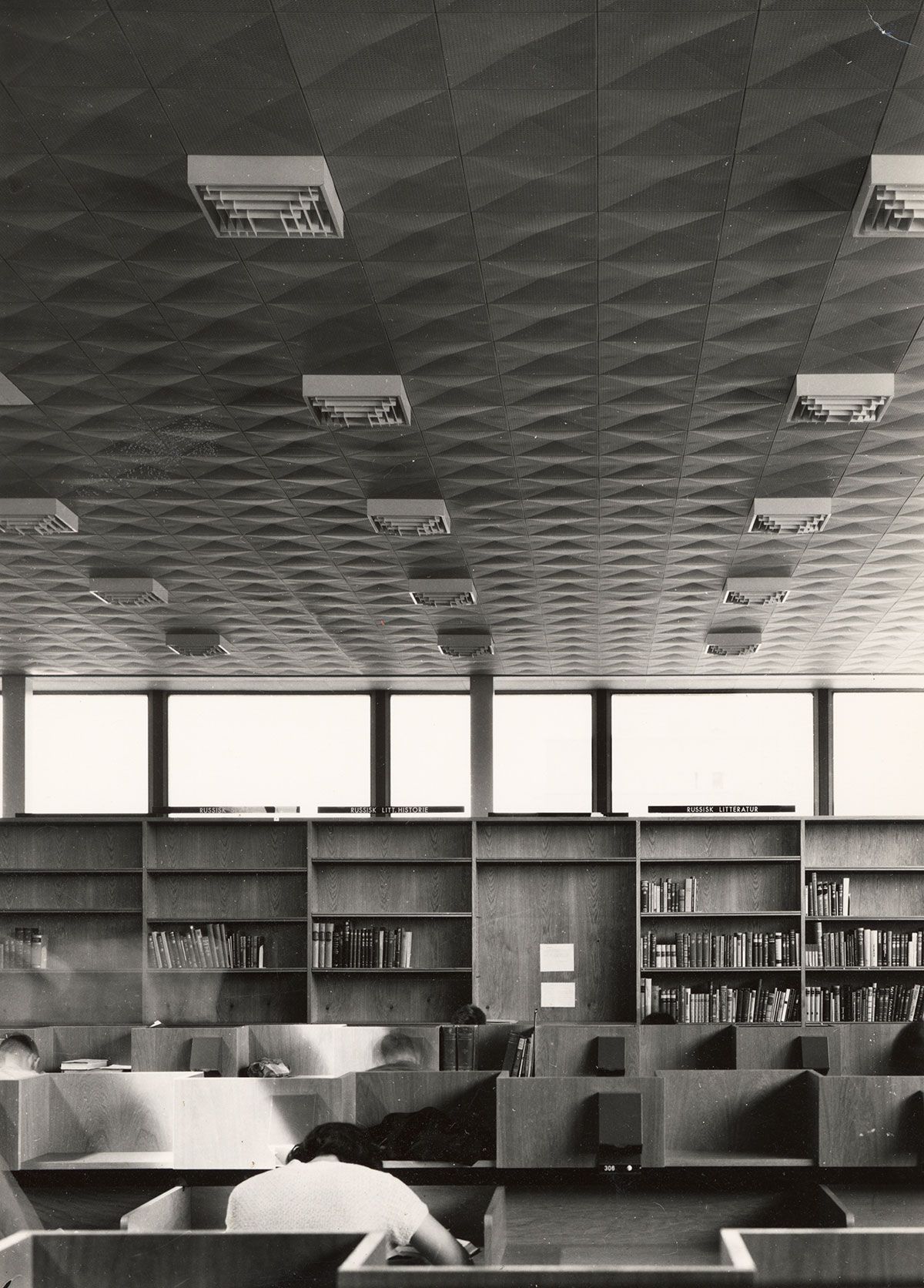 Himlingen i bibliotek- og lesesal er dekket av prefabrikerte takelementer i metall. De gjør at taket får&amp;#160;en viktig rolle&amp;#160;i&amp;#160;interiøret. Her er det også mennesker - studenter!
1963-1965. Fotograf: Teigens fotoatelier.&amp;#160;
